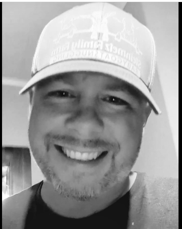 Justin smiling in a baseball cap.